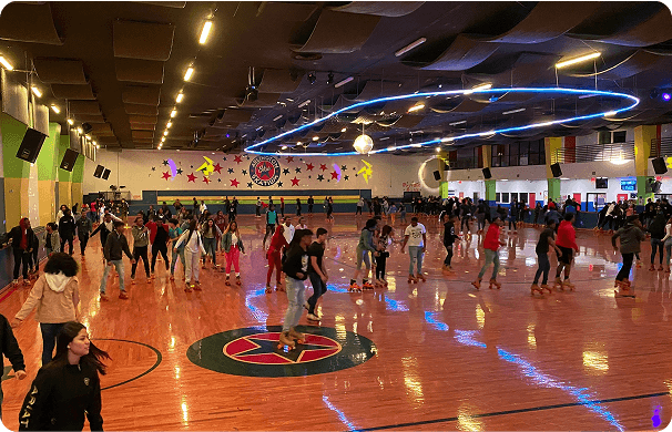 A lively roller-skating session at Arlington Skatium, with skaters gliding across the neon-lit rink and groups of people enjoying the space around the floor.